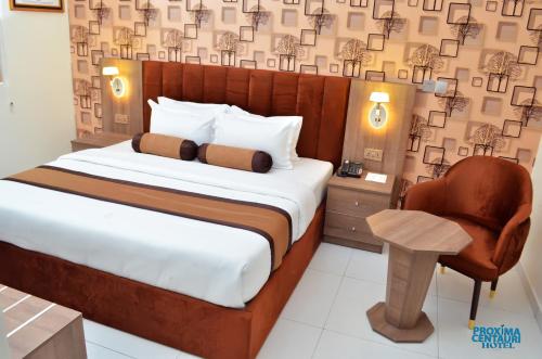 ein Schlafzimmer mit einem großen Bett und einem Stuhl in der Unterkunft Proxima Centauri Hotel in Port Harcourt