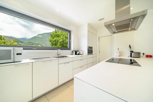 a kitchen with white cabinets and a large window at Villa Shangrila in Naturno