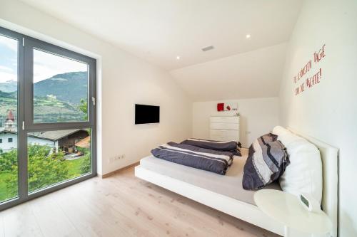 a white bedroom with a bed and a large window at Villa Shangrila in Naturno
