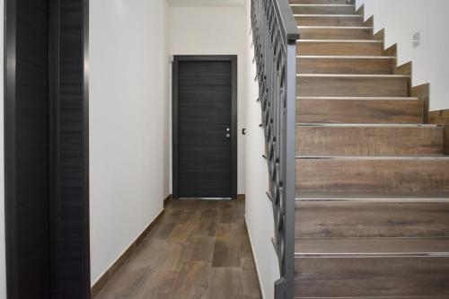a staircase with wood floors and a black door at Domus Solis in Pachino