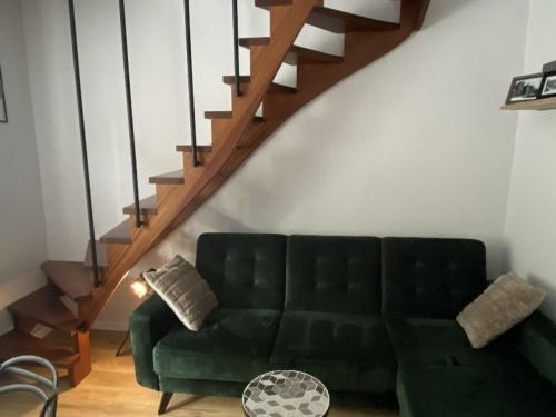 a living room with a green couch and a staircase at Apartament Schodami do Nieba in Bytom