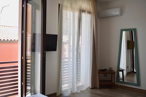 a bedroom with white curtains and a mirror at Domus Solis in Pachino