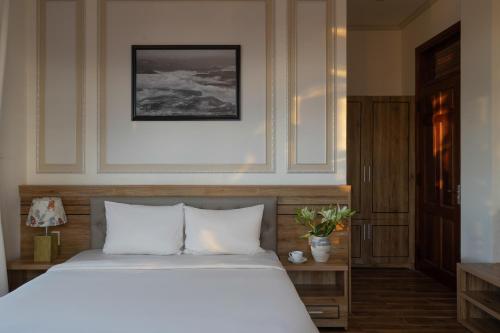 a bedroom with a white bed and a framed picture at Moon Valley Villas Đà Lạt in Xuan An