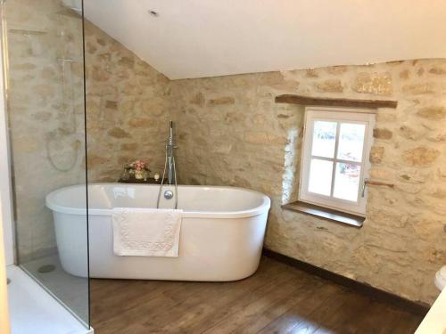 een badkamer met een bad en een raam bij Charmant cottage à la campagne in Marval