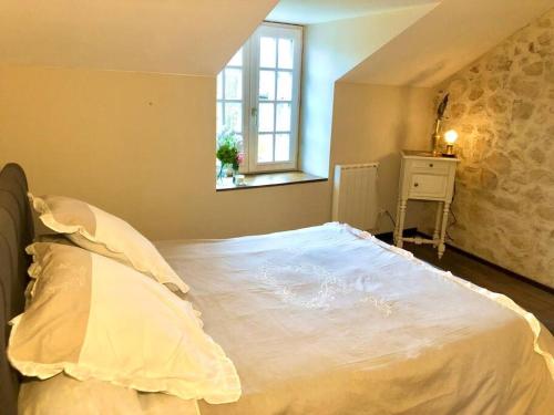 een slaapkamer met een groot wit bed en een raam bij Charmant cottage à la campagne in Marval