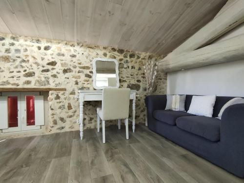 ein Wohnzimmer mit einem blauen Sofa und einem Schreibtisch in der Unterkunft Le Mas du Martinet in Anduze
