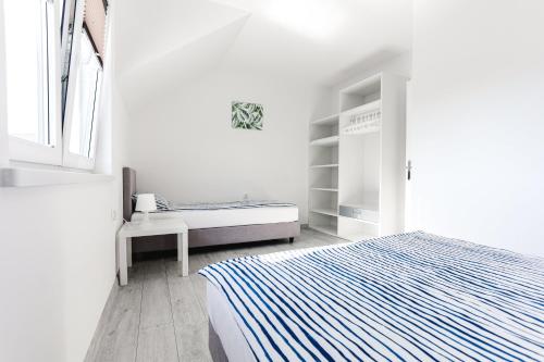 a white bedroom with a bed and a window at DOMKI APARTAMENTOWE BARKA in Karwia