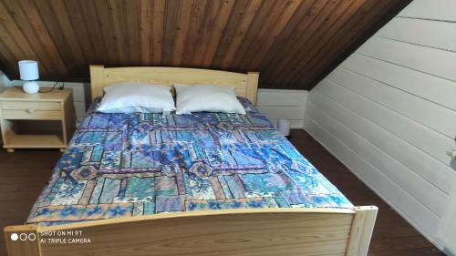 Una cama con edredón en una habitación en Le petit chalet en Gapennes