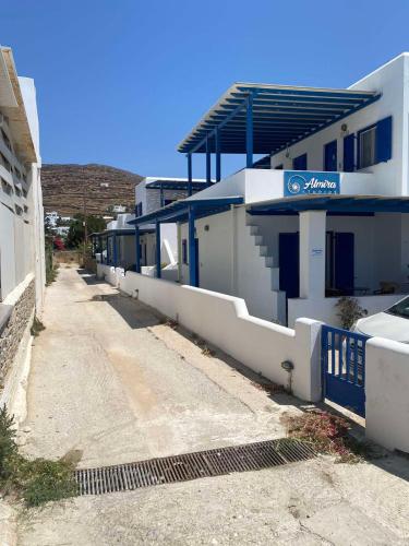 a white building with a blue fence next to a street at Fabio Studios in Kionia