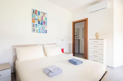 1 dormitorio con 1 cama blanca y 2 toallas en Spazioso appartamento a 5 minuti a piedi dal mare, en Massa