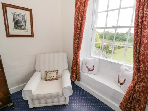 a white chair sitting in a room with a window at Glapthorn Manor in Peterborough