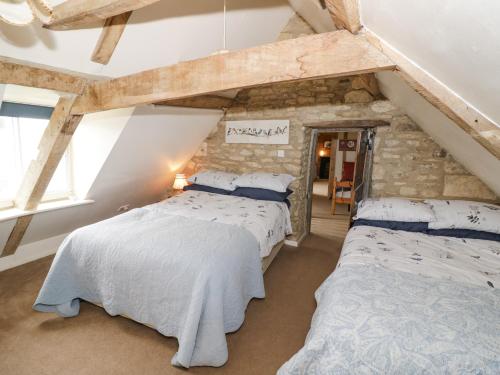 2 Betten in einem Zimmer mit einer Steinmauer in der Unterkunft Glapthorn Manor in Peterborough
