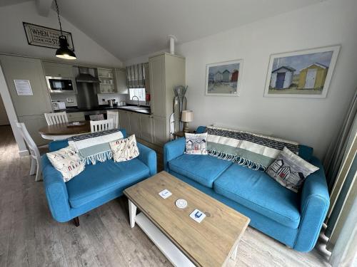 a living room with a blue couch and a table at Azure Beach House - Part of the The Bay Filey Holiday Village with pool, gym and direct beach access, pub, restaurant, tennis and meadows walks in Filey