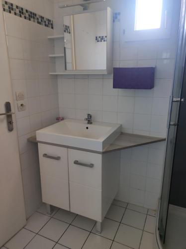 a white bathroom with a sink and a mirror at Le Hameau du Gîte in Saint-Augustin