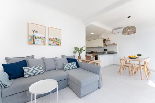 ein Wohnzimmer mit einem grauen Sofa und einem Tisch in der Unterkunft Agaete White&Blue House in Agaete