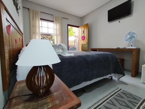 1 dormitorio con 1 cama y 1 mesa con lámpara en Pouso Casa da Vovó en Tiradentes