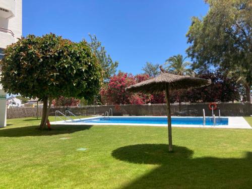 a swimming pool with an umbrella and two trees at APARTAMENTO GEMINIS VISTA - WiFi - Parking in El Puerto de Santa María