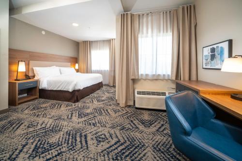 Candlewood Suites Charleston – Mt. Pleasant, an IHG Hotel في تشارلستون: غرفه فندقيه بسرير وكرسي ازرق
