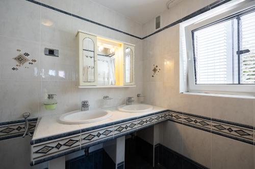 a bathroom with two sinks and a window at Old Road Rooms and Apartments with Pool in Portorož