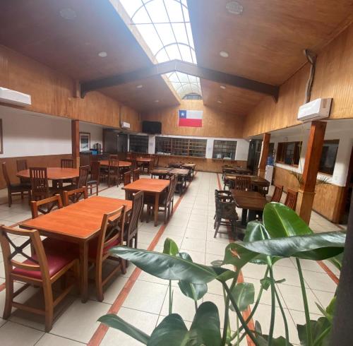 un restaurante con mesas y sillas de madera y una planta en Hotel Palermo Quintero en Quintero