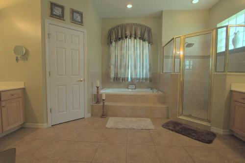达文波特Entire home with pool and lake view and Golf course by Disney的带浴缸和淋浴的大浴室