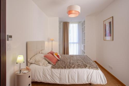 - une chambre blanche avec un grand lit et des oreillers roses dans l'établissement Casa Anatella, à San-Martino-di-Lota