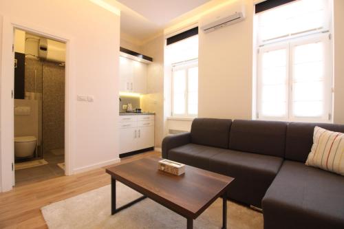 een woonkamer met een zwarte bank en een tafel bij MAGIC Apartments in Sarajevo