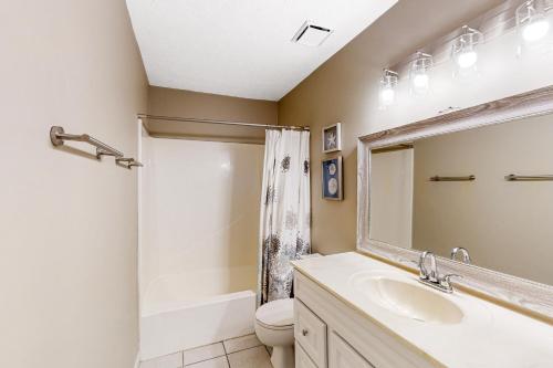 a bathroom with a sink and a toilet and a mirror at Southwind C-2 in Panama City Beach