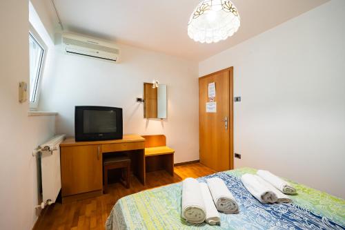 a bedroom with a bed and a tv on a desk at Old Road Rooms and Apartments with Pool in Portorož