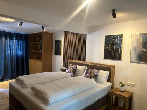 um quarto com uma cama grande com lençóis brancos e almofadas em Gasthaus zu den 7 Winden em Spaichingen