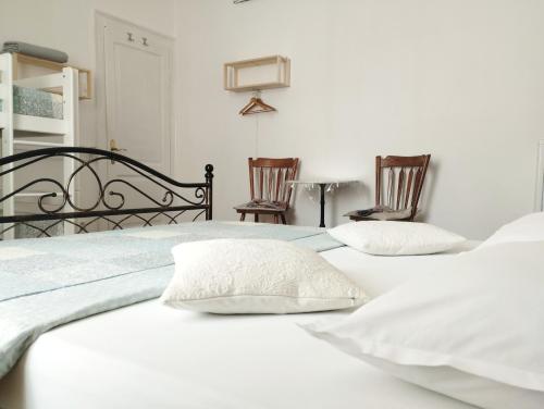 イゾラにあるGuest House Izolaの白いベッド1台(椅子2脚付)が備わるベッドルームです。