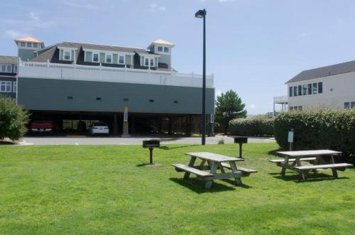 two picnic tables in a field in front of a building at FFR114 - Nemo's Retreat in Kill Devil Hills