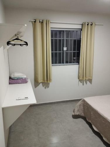Habitación con cama y ventana con cortinas. en Residencial Casa Grande - Apto 02, en Santa Cruz Cabrália