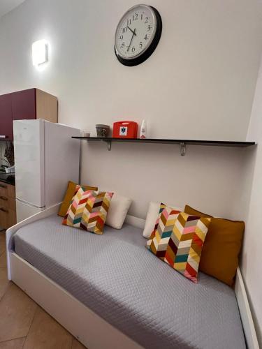 a bed with pillows and a clock on a wall at Casa MiLù in Canneto