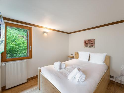 une chambre avec un lit avec des draps blancs et une fenêtre dans l'établissement Appartement rénové avec balcon - Centre de Courchevel 1850, proche remontées mécaniques - FR-1-564-87, à Courchevel