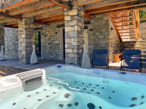 un bain à remous dans un bâtiment en pierre avec des chaises dans l'établissement Chalet de prestige avec jacuzzi, sauna et cinéma - FR-1-570-42, à Saint-Martin-de-Belleville