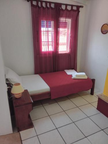 a small bedroom with a bed with a red window at The Captain in Elafonisos