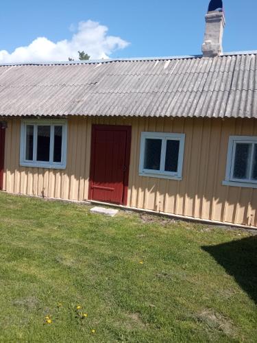 ein Haus mit einer roten Tür und einem Hof in der Unterkunft Kuru village in Kuru