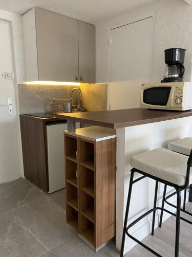 une cuisine avec un comptoir, un four micro-ondes et un tabouret dans l'établissement Mansarde Cannes, à Cannes