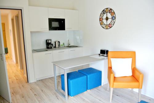 a white kitchen with a table and a chair at Bernsteinsee Hotel&Ferien in Sassenburg