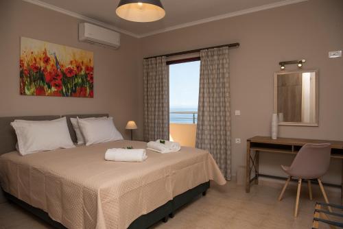 a bedroom with a bed and a desk and a window at Akrotiri Sea View Suites in Zakynthos Town