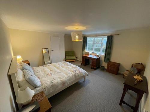 Schlafzimmer mit einem Bett, einem Schreibtisch und einem Fenster in der Unterkunft Manor Farm Holiday Cottages in Chard