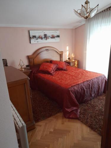 a bedroom with a bed with a red comforter at Atico augaboa in Cangas de Morrazo
