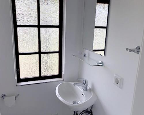 a white bathroom with a sink and a mirror at Bernsteinsee Hotel&Ferien in Sassenburg
