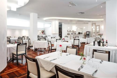 Hotel Carlo Felice في ساساري: غرفة طعام مع طاولات وكراسي بيضاء
