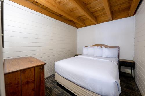 a bedroom with a white bed and a wooden table at Depe Dene Lakeside Resort in Lake George