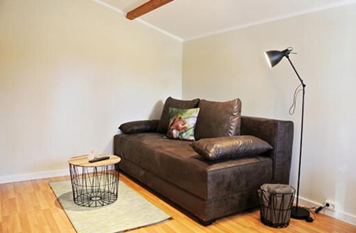 a brown couch in a living room with a lamp at Bernsteinsee Hotel&Ferien in Sassenburg