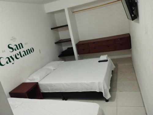 Habitación pequeña con 2 camas y espejo. en Hotel San Cayetano, en Ocaña