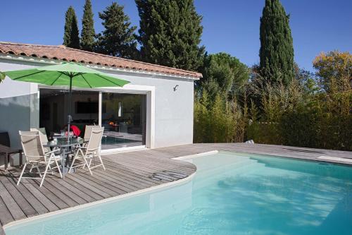 eine Terrasse mit einem Tisch und einem Sonnenschirm neben einem Pool in der Unterkunft Belle Villa moderne avec piscine et jardin in Solliès-Pont
