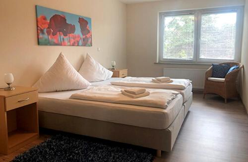 a bedroom with two beds and a desk and a window at Bernsteinsee Hotel&Ferien in Sassenburg